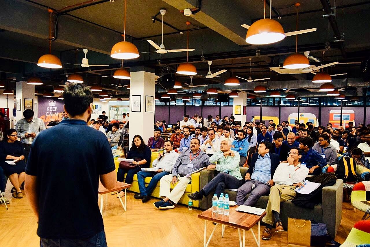 A startup founder pitching to an audience of investors and corporate leaders